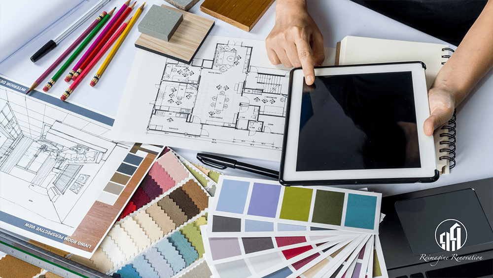 Interior designer looking at an iPad, color swatches, and a blueprint of home renovations