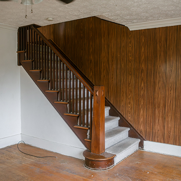 Outdated staircase with dark paneled walls