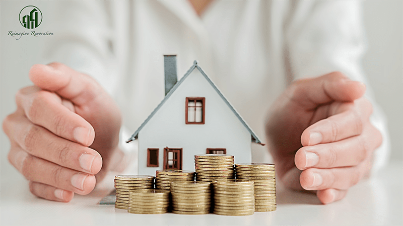 A model of a house with coins stacked up in front of it with a homeowner's hands surrounding it